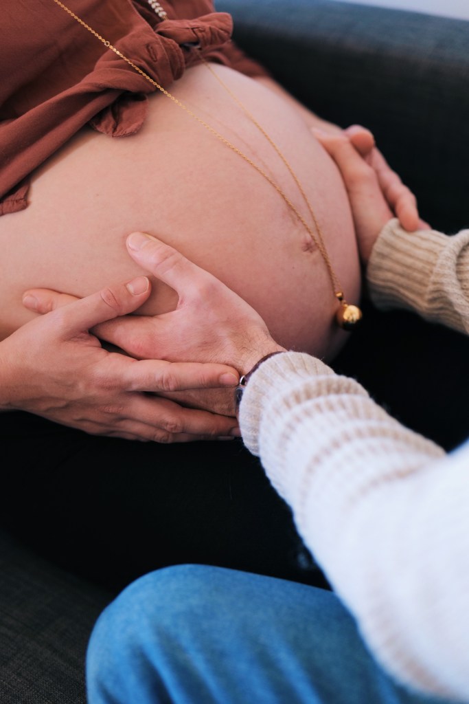 Séance d'haptpnomie, le père met la main sur le ventre de sa femme pour entrer en communication avec bébé